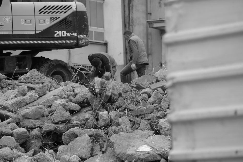 A demolition site with an excavator and broken masonry.