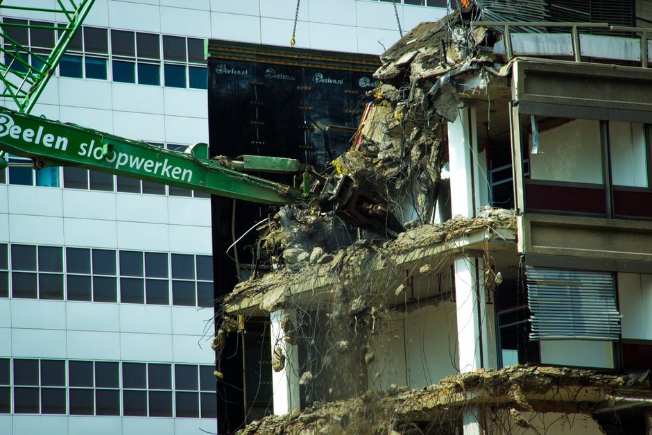 A demolition site with an excavator and broken masonry.