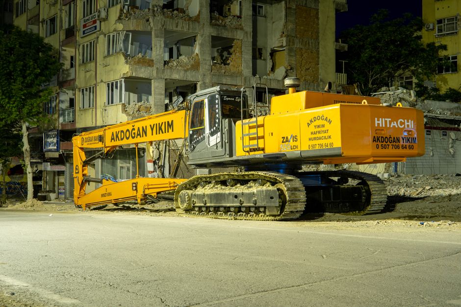 A demolition site with an excavator and broken masonry.
